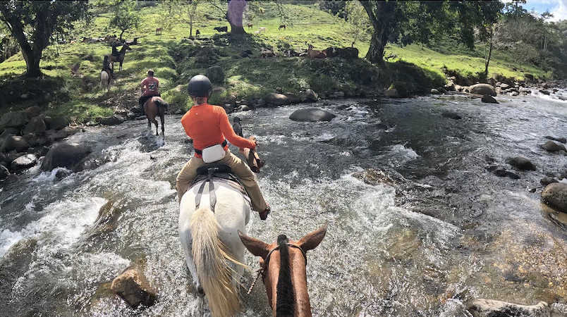 Riders crossing a rushing river on horseback through the Venado countryside